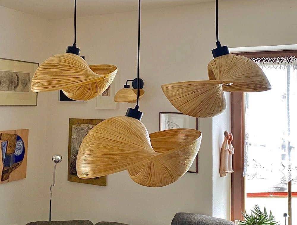 Four wooden, spiral-shaped pendant lights hanging in a modern living room.