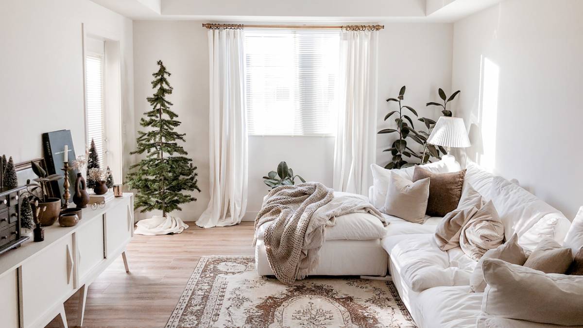 Bright, cozy living room decorated for Christmas with a sofa, tree, and festive accessories.