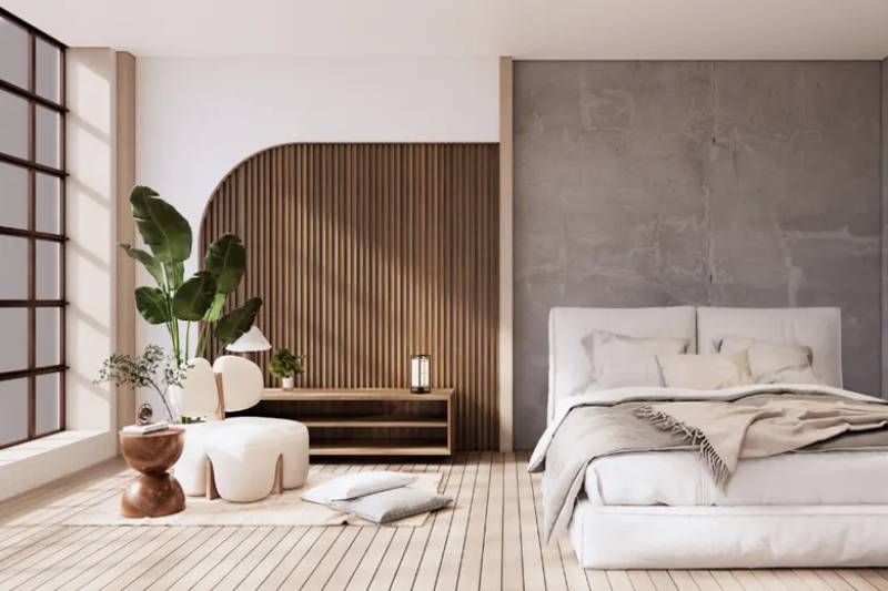 Modern bedroom with a white bed, wooden wall panelling, concrete accent wall, and indoor plants.