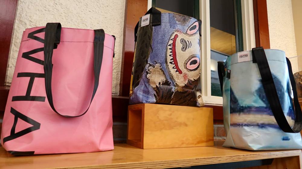 Three tote bags displayed on a shelf, featuring pink, patterned, and sky blue designs.