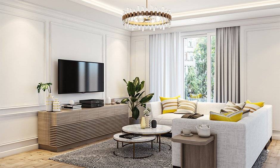 Modern living room with white sofa, TV, wooden console, and large windows letting in natural light.