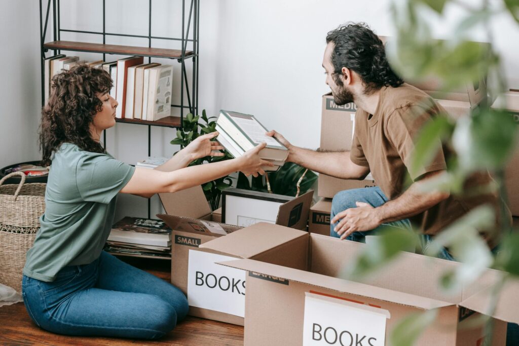 A man and a woman pack books into boxes in a home library.