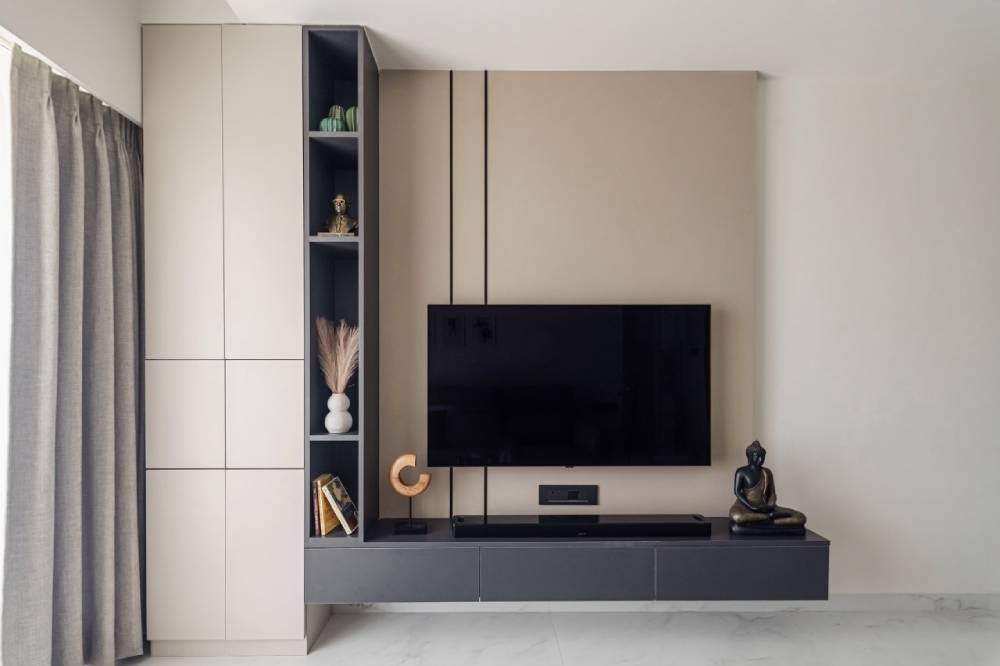 Modern living room with beige walls, featuring a TV, a grey cabinet, and a decorative shelf unit.