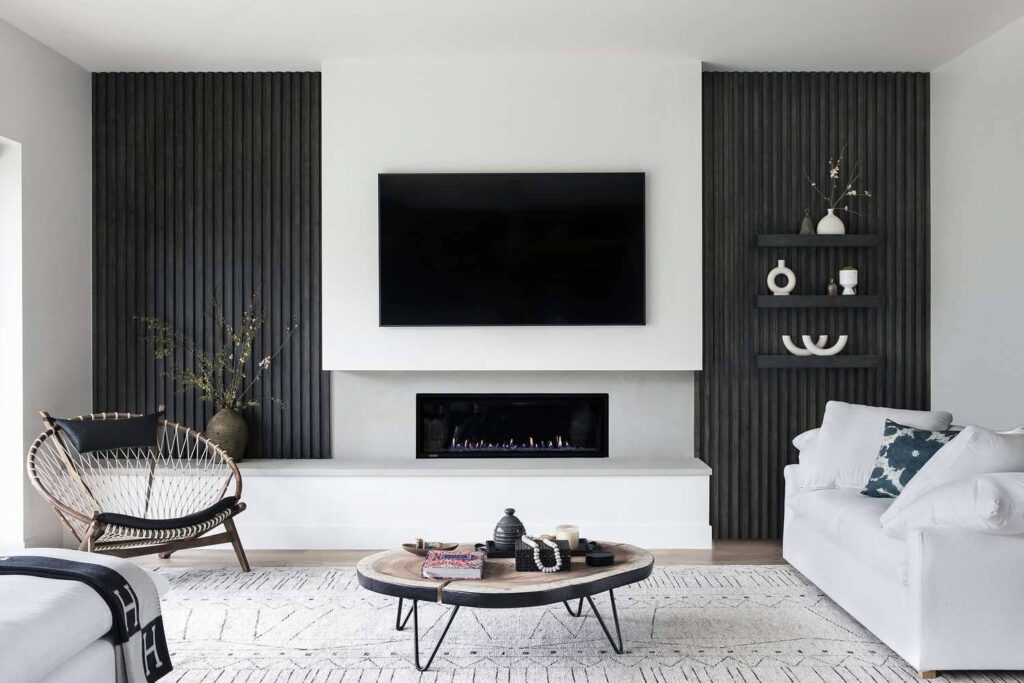 Modern living room with white sofa, oval coffee table, mounted TV, and dark wood paneling.