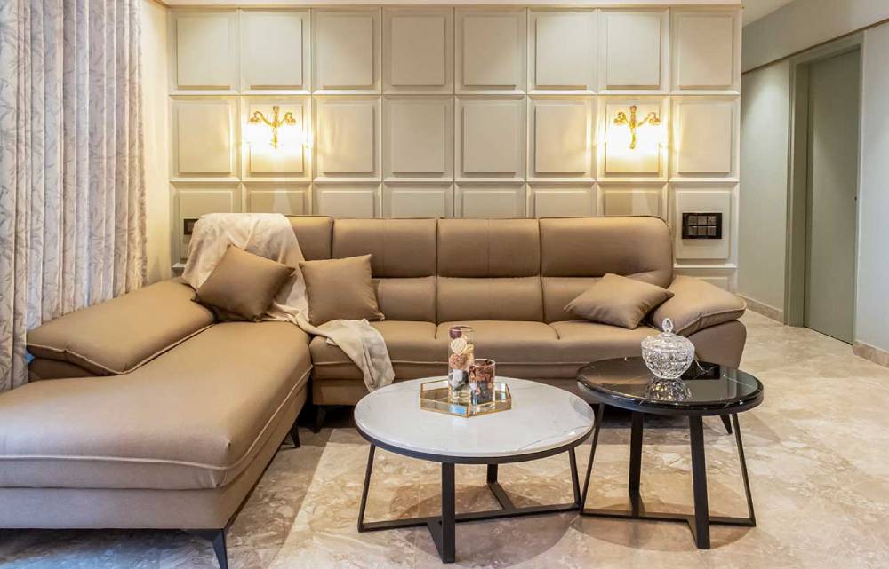 Modern living room with beige sectional sofa, elegant wall panels, and two round coffee tables.