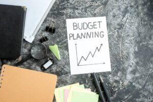 Office supplies and a "Budget Planning" paper with a line graph on a textured dark background.