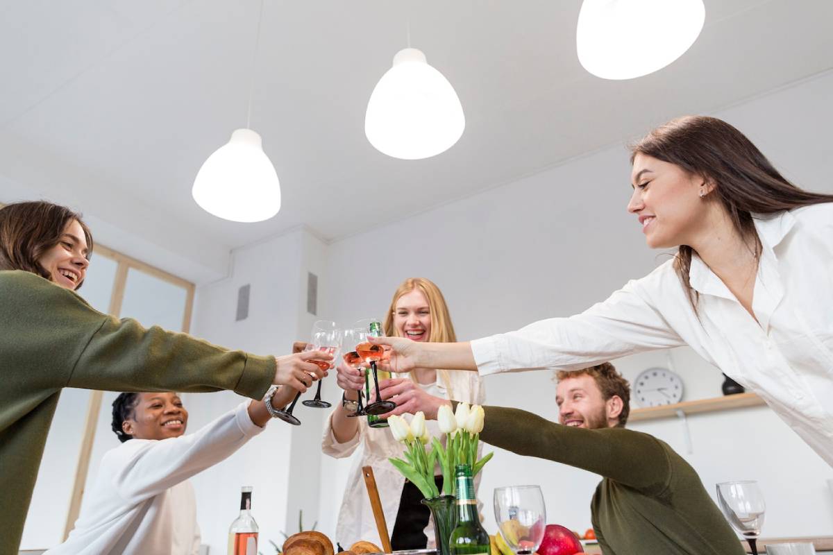 Group of friends toasting with wine glasses at a bright and cheerful dinner party. 