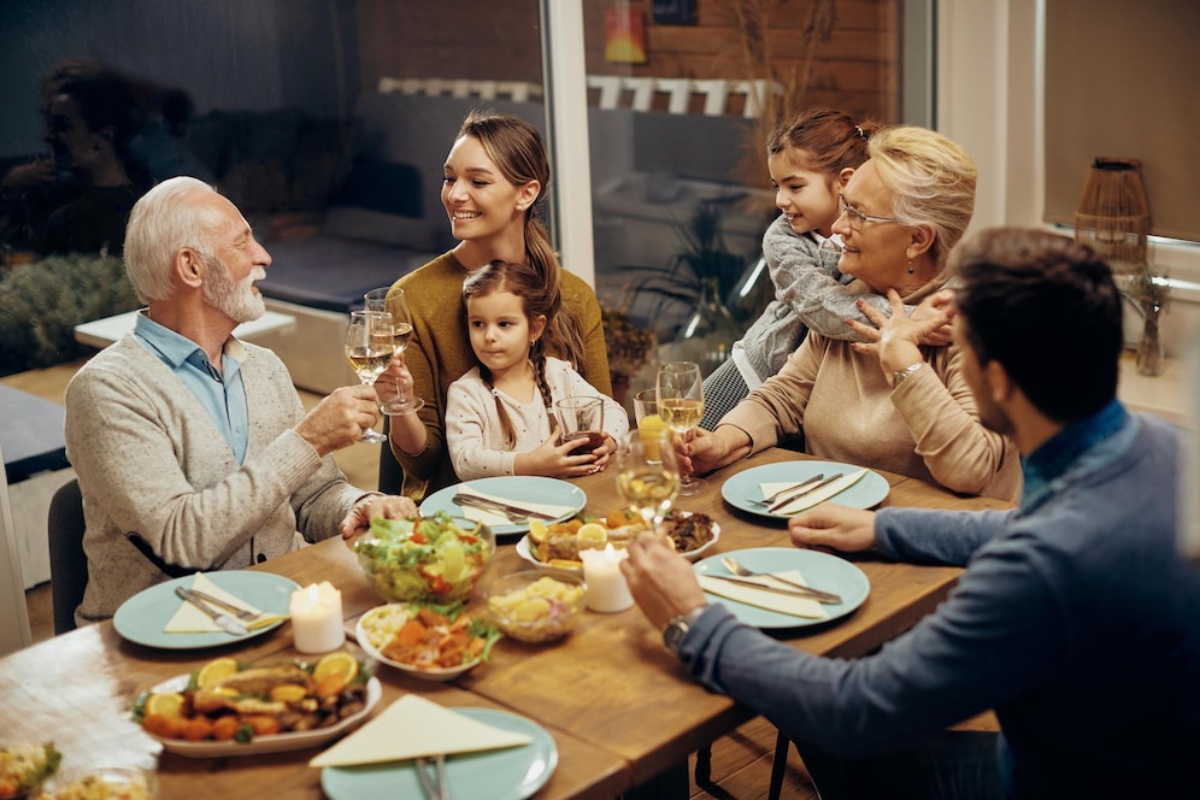 A multi-generational family enjoying a meal together, with smiles and toasts around a dining table.